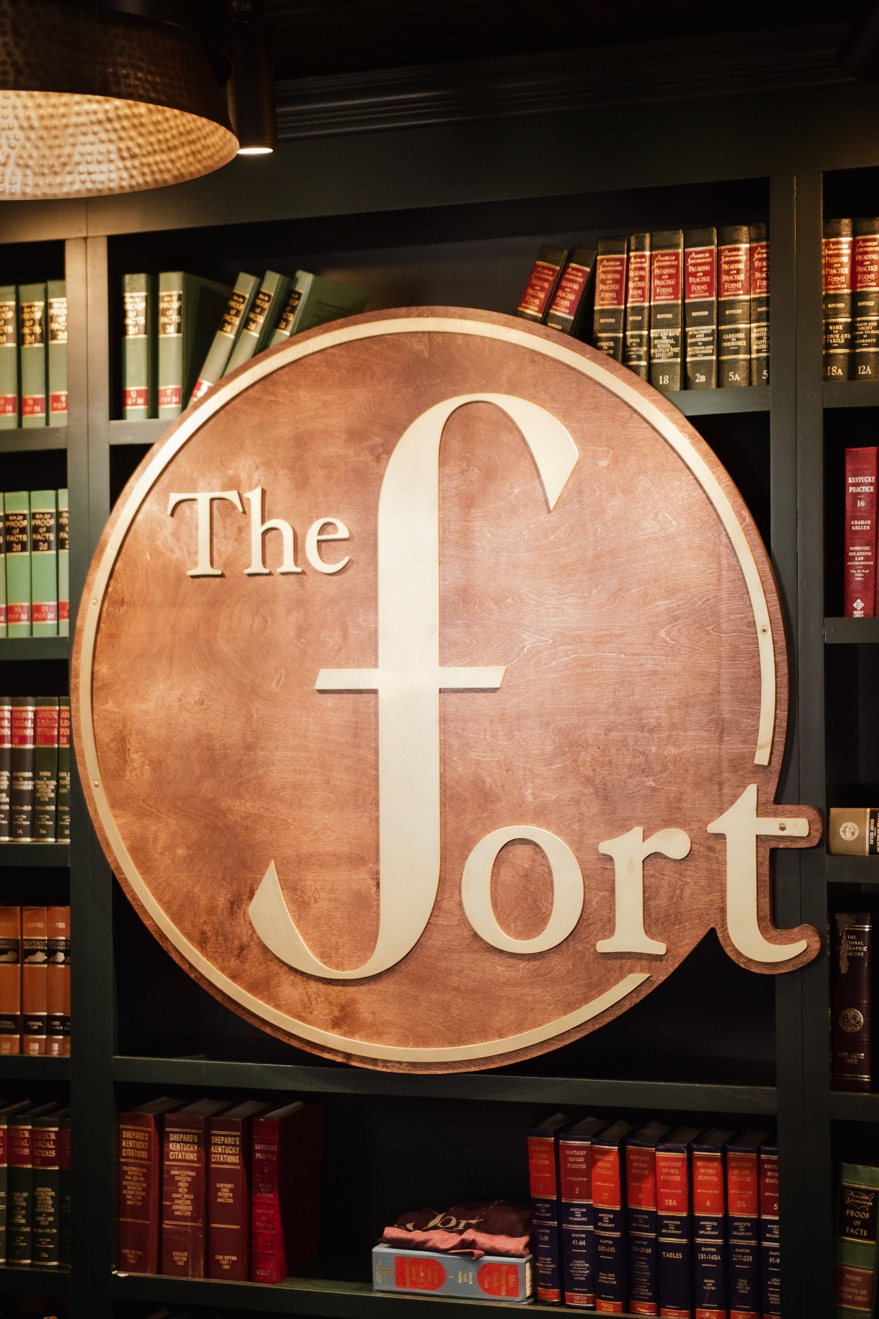 The copper-and-gold 'The Fort' emblem mounted against shelves of legal volumes