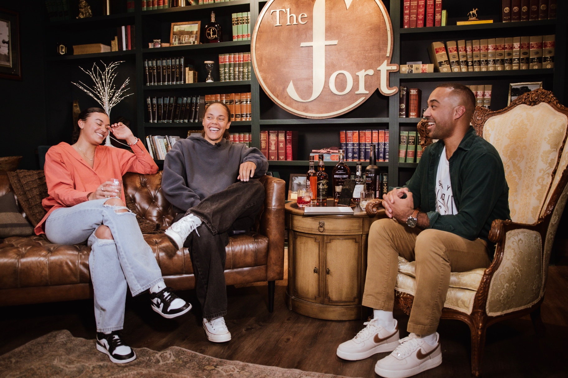 Host Arian Green in conversation with two guests at the table during a taping of AI on the Rocks at The Fort