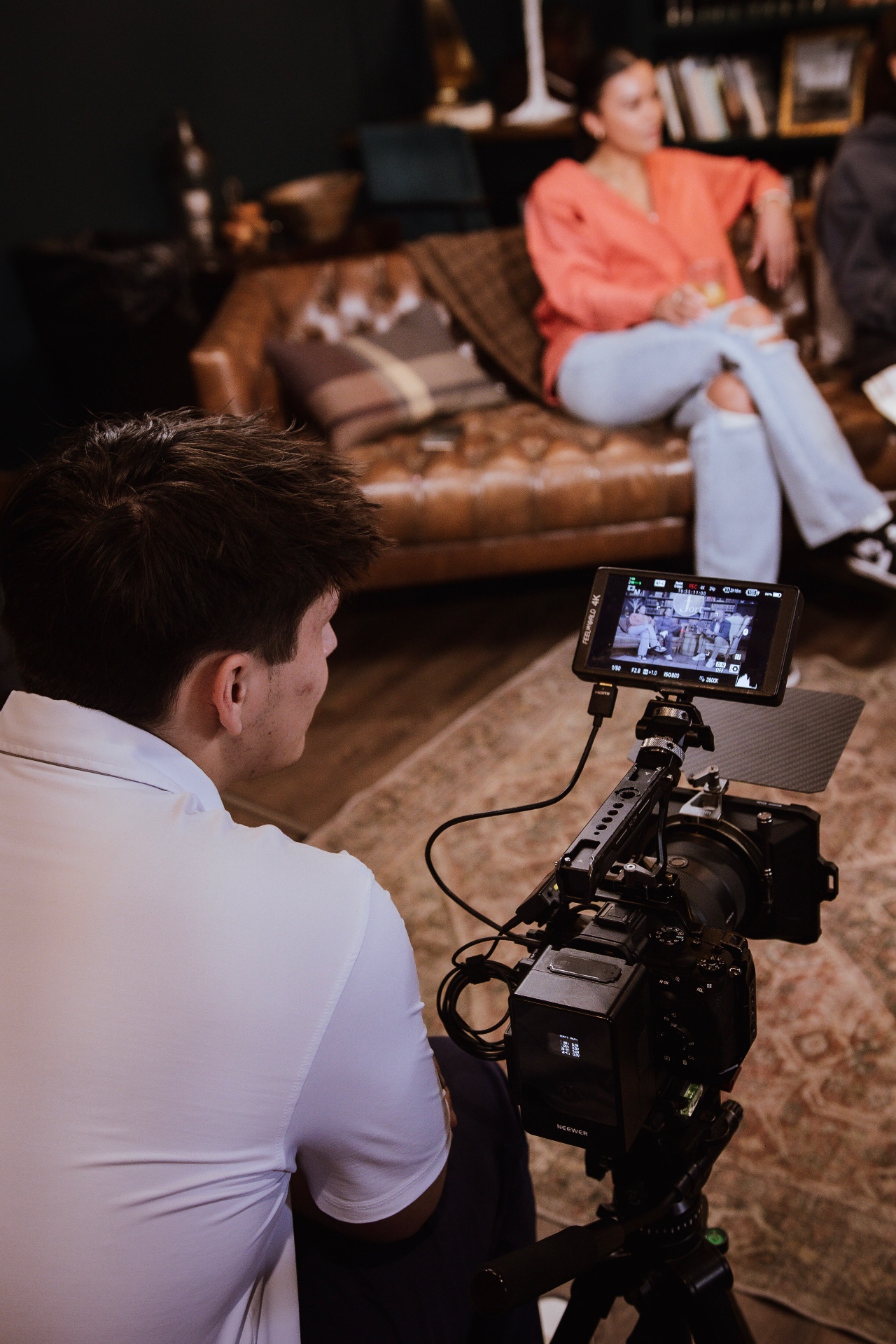A camera operator filming a guest on the leather couch at The Fort during a taping of AI on the Rocks
